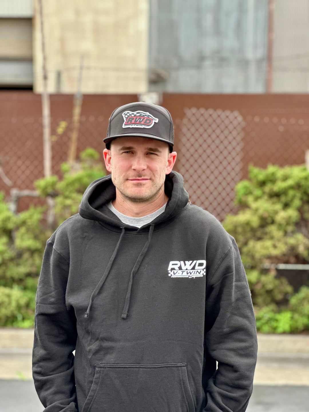 Man looks at the camera outdoors while wearing an RWD V-Twin hat and sweatshirt
